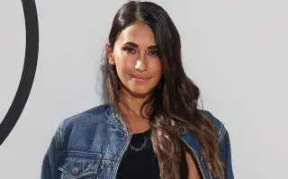 Antonela Roccuzo en un desfile de LV con una campera de jean y un vestido negro
