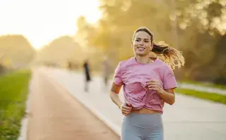 Mujer corriendo por un camino arbolado
