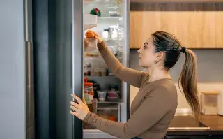 Cómo conservar frutas y verduras por más tiempo y evitar tirar comida una mujer revisa alimentos de la heladera