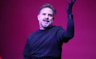 Juan Pablo Geretto levantando un brazo, vestido de negro.
