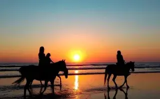 Fines de semana largos 2026: 5 escapadas cercanas para descansar antes de fin de año Unas personas cabalgando a la orilla del mar.