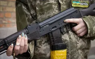 Una mujer armada de defensa civil sostiene un rifle de asalto Kalashnikov mientras patrulla una calle vacía debido al toque de queda en Kiev.