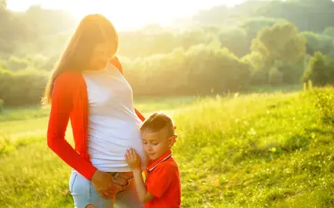 Mujer embarazada junto a su otro hijo.