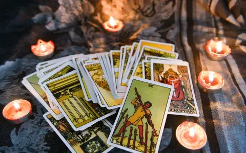 Un mazo de tarot sobre una tela y unas velas encendidas.