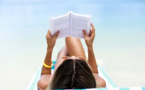 Una mujer leyendo en la playa