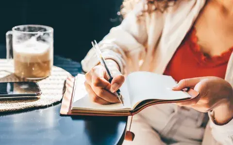 Una mujer escribiendo en un cuaderno.