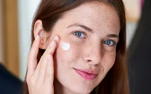 Una mujer poniendose crema en el rostro