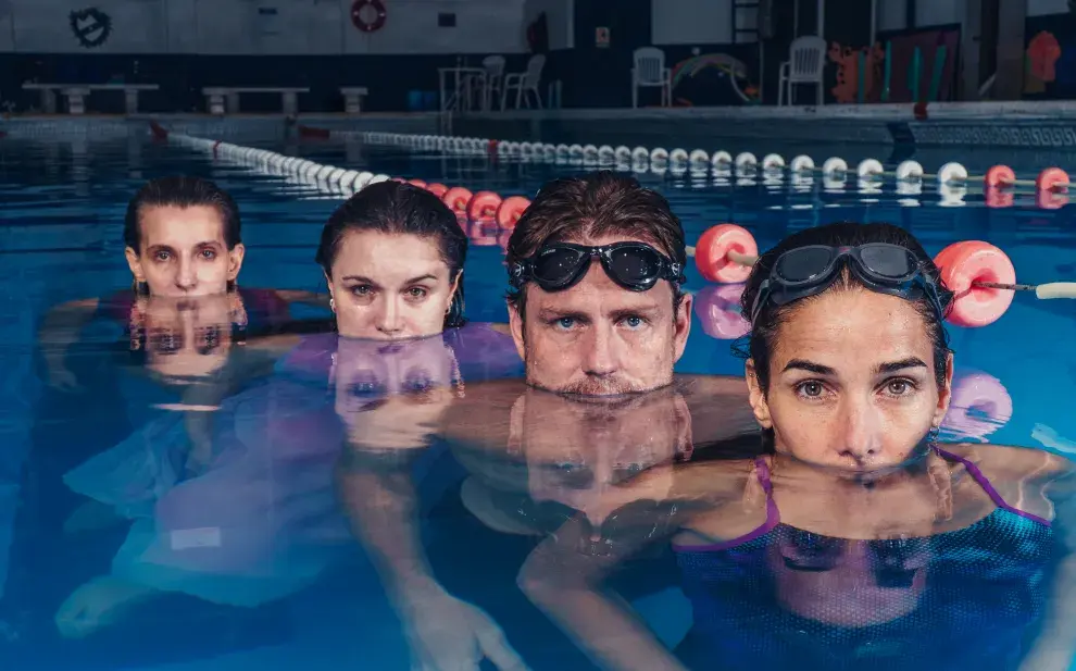 4 actores sumergidos en una pileta de natación.
