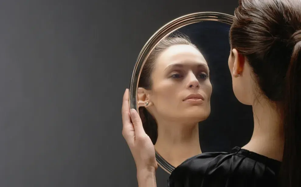 Foto de mujer mirándose en un espejo.